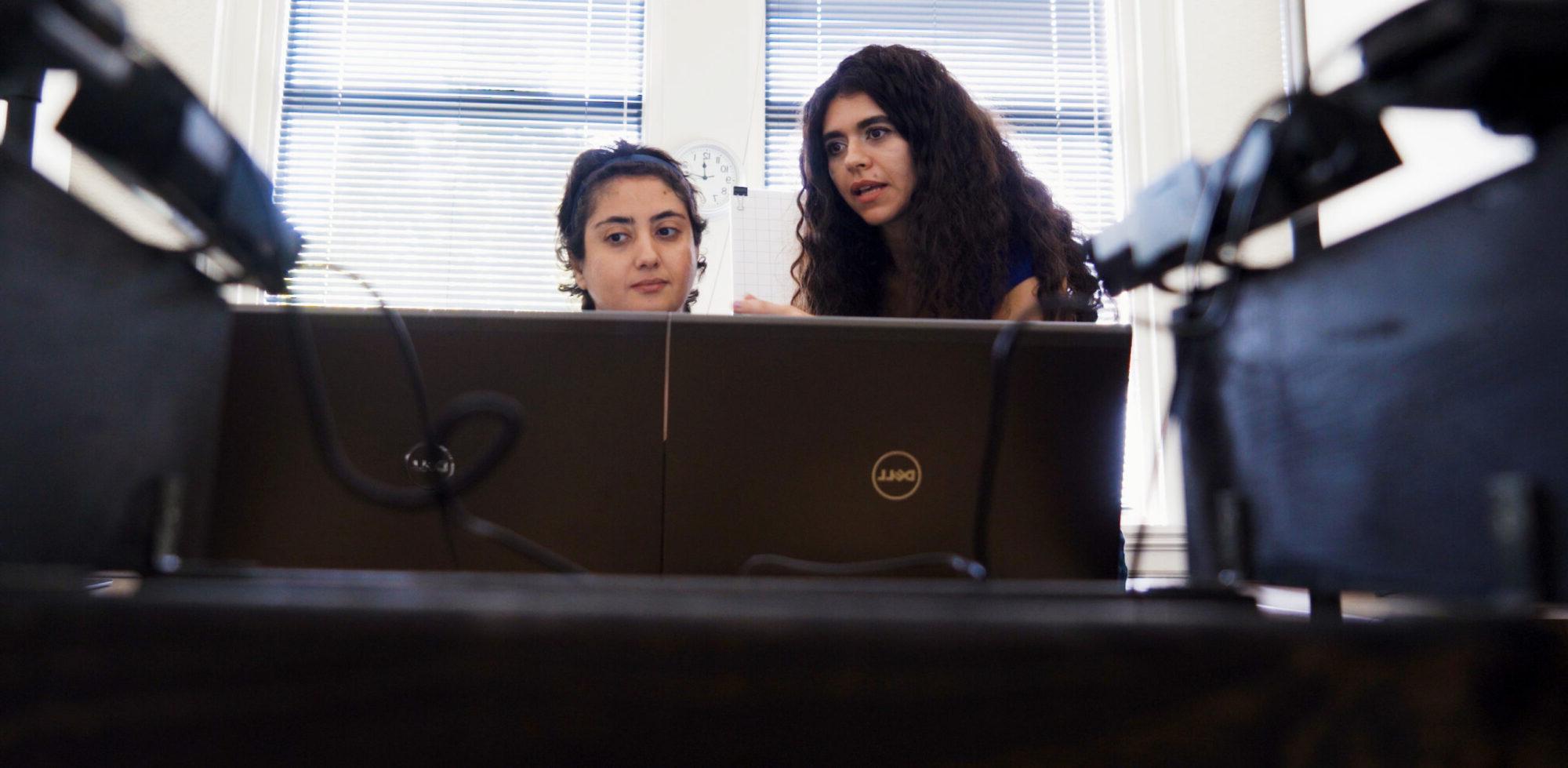 Two females, one is teaching the other something about the computer.